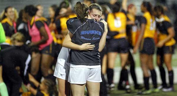 As American Heritage players celebrate in the background, Ponte Vedra High’s Callie Delaney hugs a teammate following the Sharks’ 2-0 loss in the Class 3A girls soccer state championship game played at Melbourne High School. (photo by Rob DeAngelo)