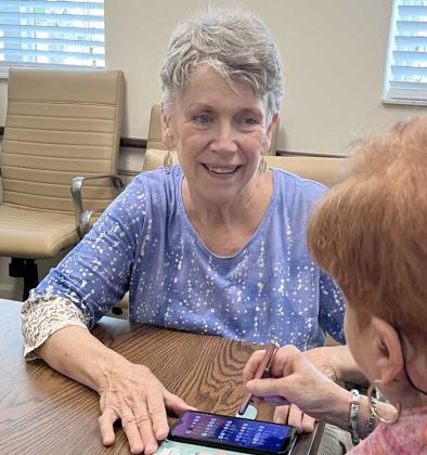 Mary Roberts helps a resident with her phone. (photo by Linda Borgstede)