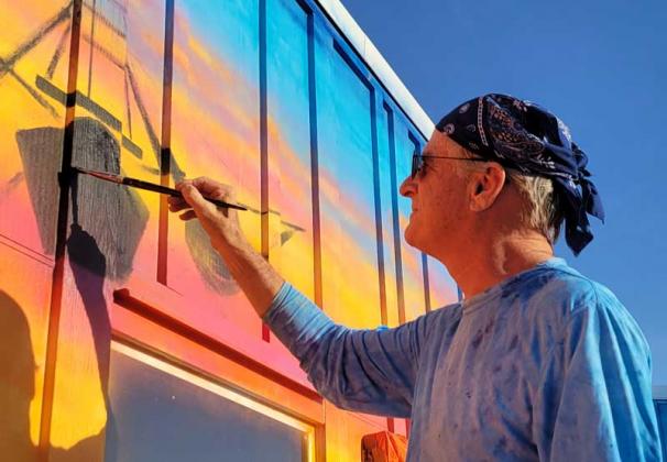 Gary Mack works on a mural covering the deck wall at Singleton's Seafood Shack. (photo by Liza Mitchell)