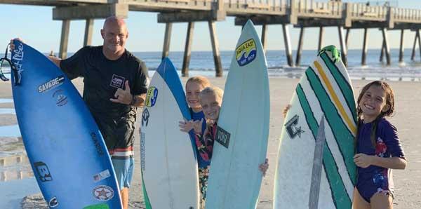 Jason Motes teaches some young surfers. From left are Motes, Ansley West, Coral Sasser and Romie Stalnaker. (photo by Terry Hanna @surfcountry)