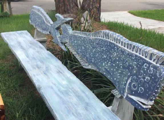 A carved bench with a whale theme.