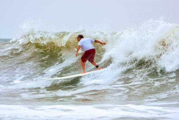 Mitch Kaufmann, organizer of Wavemasters Pro-Am for more than 25 years, catches a wave as Hurricane Larry passes offshore. (photo by Roxanne De Sousa)