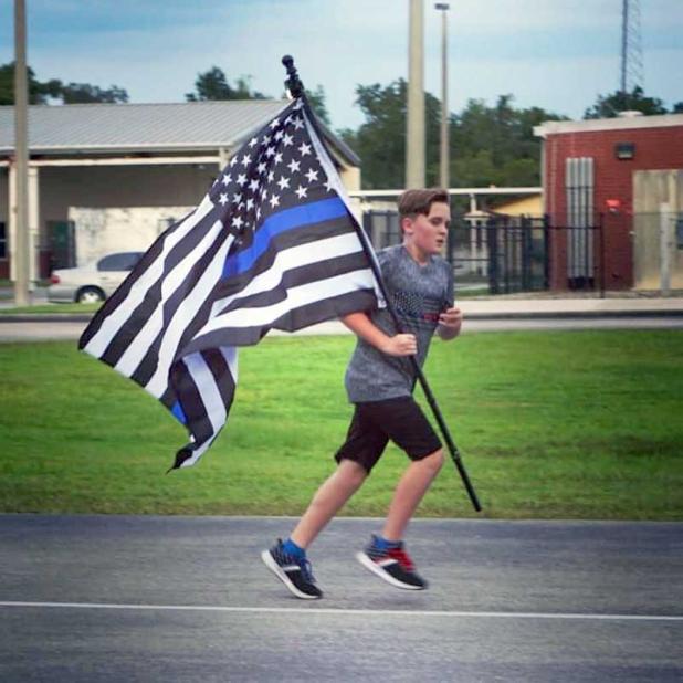 Zechariah Cartledge runs for a fallen First Responder while carrying an American flag. (photo from Running 4 Heroes Inc. Facebook)