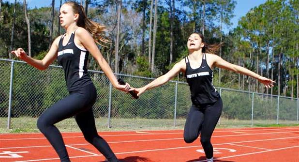 Ponte Vedra High’s Reagan Darrah, left, receives the baton from teammate Emma Bennett during the first exchange of the girls 4 x 200 meter relay race at last Saturday’s Craig Speziale Invitational track meet. The Sharks finished second in the race and the girls team won the meet with 174 points. (photo by Rob DeAngelo)