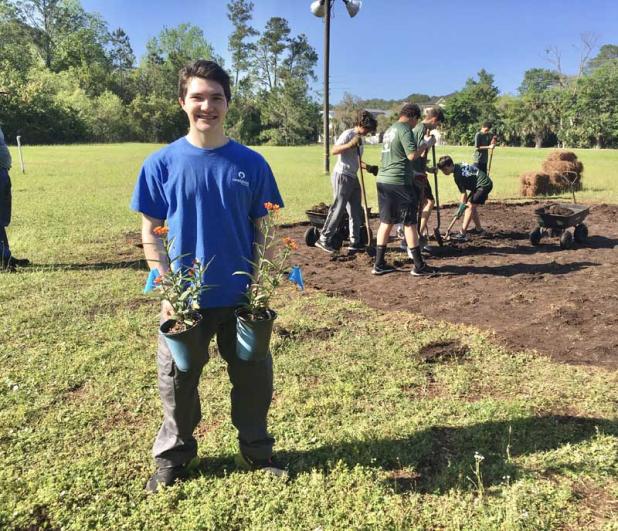Local Scout Nicholas Storm shows some native Florida plants while members of his Boy Scout Troop 277 prepare the ground for the plantings. The finished garden will be open to the public at Lord of Life Lutheran Church in Ponte Vedra Beach. (photo by Linda Borgstede)