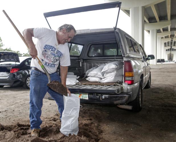 Robby Bacom of Palm Valley fills a sandbag under the Palm Valley Bridge Wednesday morning. (photo by David Rosenblum)