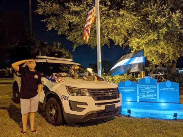 Eli Watts salutes his father's patrol car at the Jacksonville Beach Police Station.