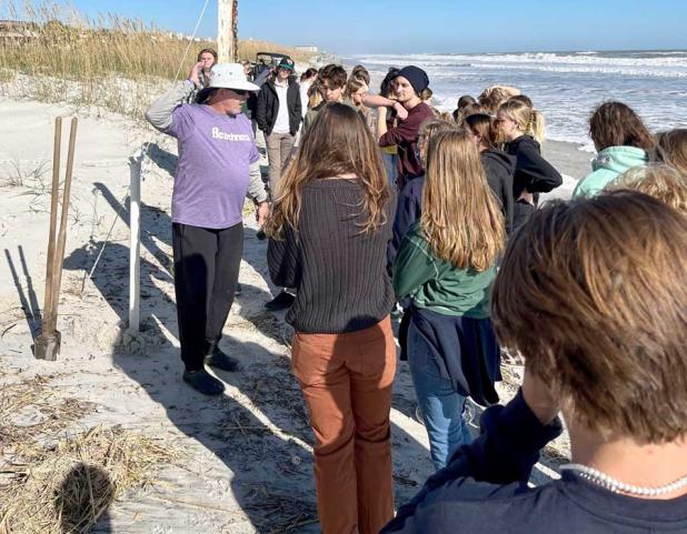 Coach Kevin Brown explains how the barriers keep the “foot traffic" out of the dunes. This allows the vegetation to grow and collect sand for building the dune. (photo submitted)