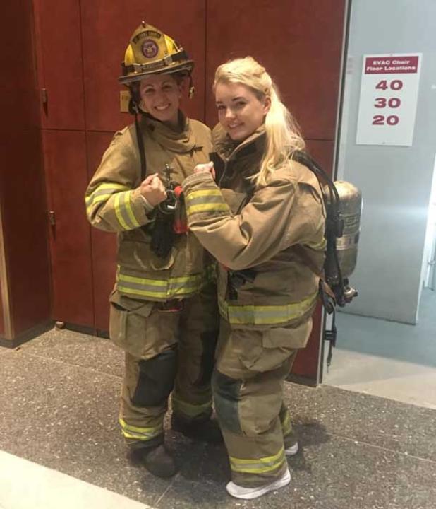 A firefighter shows Casey Feindt, right, how to wear the gear used during the Fight For Air Climb. (photo submitted)