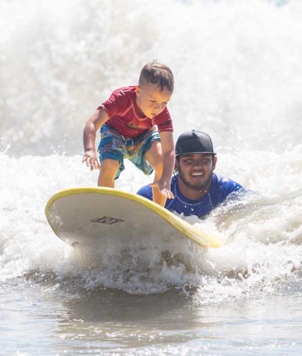 Super Grom Finley Watson and instructor Jacob Galura ride a wave. (photo by David Rosenblum)