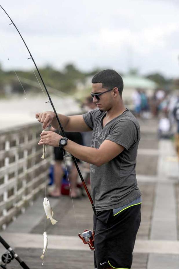 An angler takes a fish off a hook at the Jacksonville Beach Pier. The pier is a popular fishing spot for many patrons year round, and can be particularly crowded during the summer months. (photo by David Rosenblum)