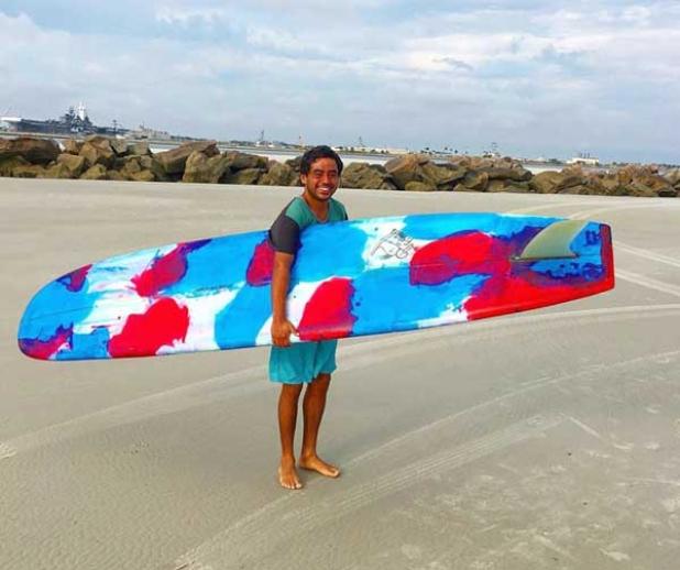Gus Fore holds his custom longboard, which was recently stolen in Atlantic Beach. (photo submitted)