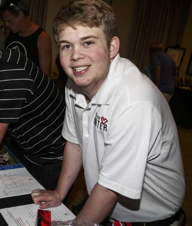 Hunter Crain takes a break from looking over sports memorabilia donated by Palm Beach Autographs for a silent auction during the 2015 COTA Heart for Hunter Golf Classic at Atlantic Beach Country Club. The event helped raise money needed for Crain’s heart transplant, which he received in Gainesville. (photo by David Rosenblum)