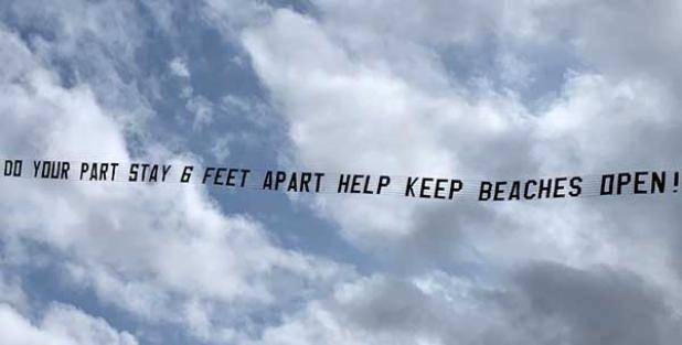 An aerial banner by the Coalition for Safe Open Beaches flies over the beachfront. (photo submitted)