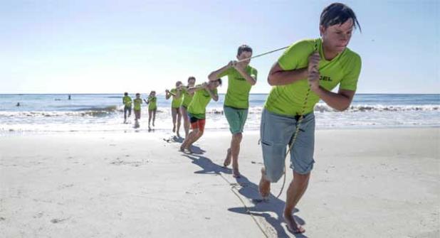Participants in the Advanced Junior Lifeguard Camp practice the landline technique, in which one lifeguard approaches the victim in the water while the remaining lifeguards remain on land and pull the victim to safety using a rope. (photo by David Rosenblum)