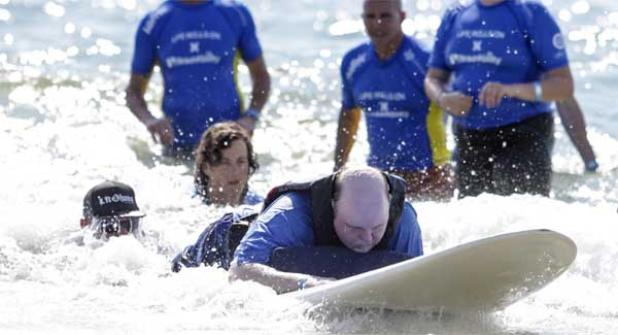 Greg Mason rides a wave to the beach under the watchful eye of volunteers. (photo by David Rosenblum)
