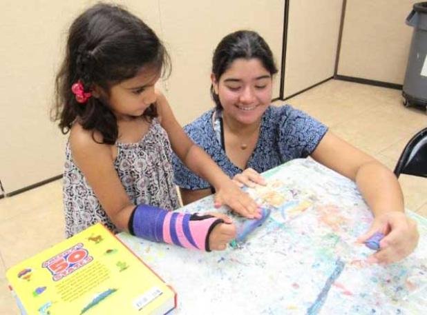 Volunteer Julia sculpting clay with a young artist. (photo submitted)